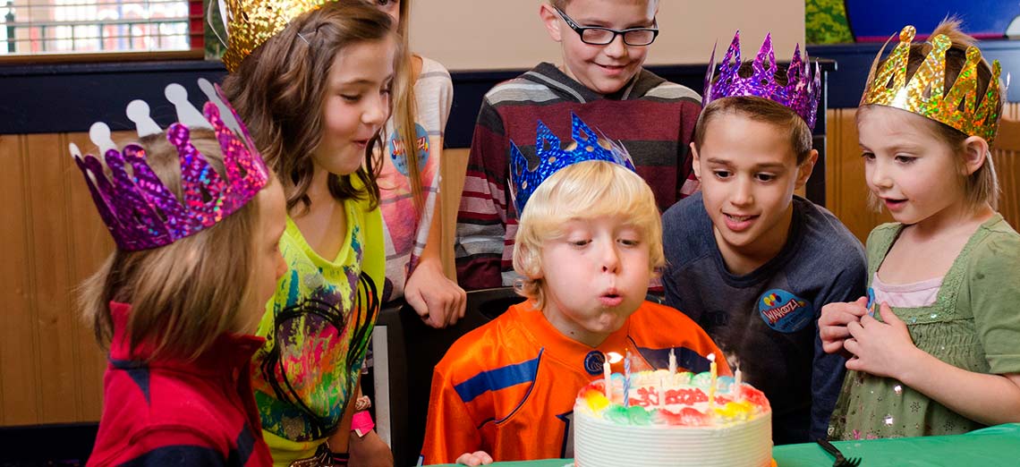 young kids watch as birthday boy blows out candles