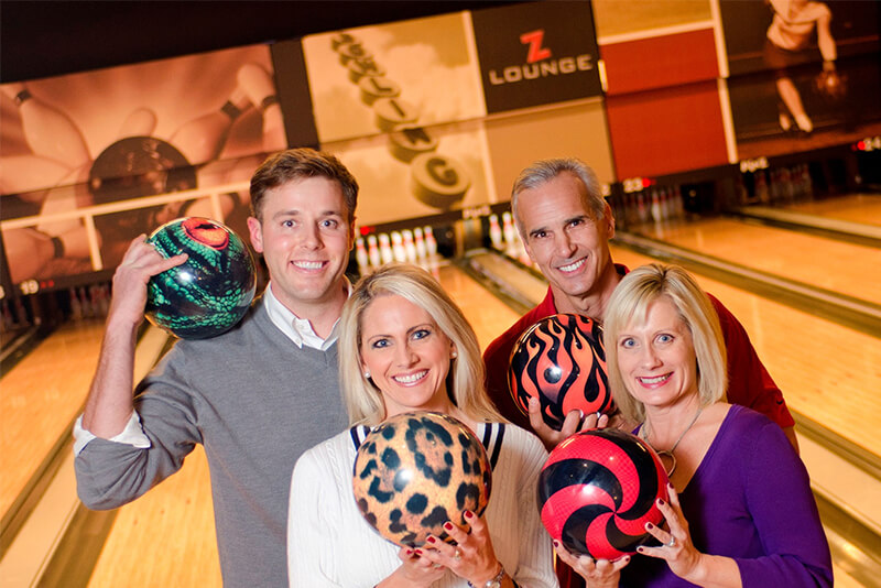 Four adults posing with bowling balls